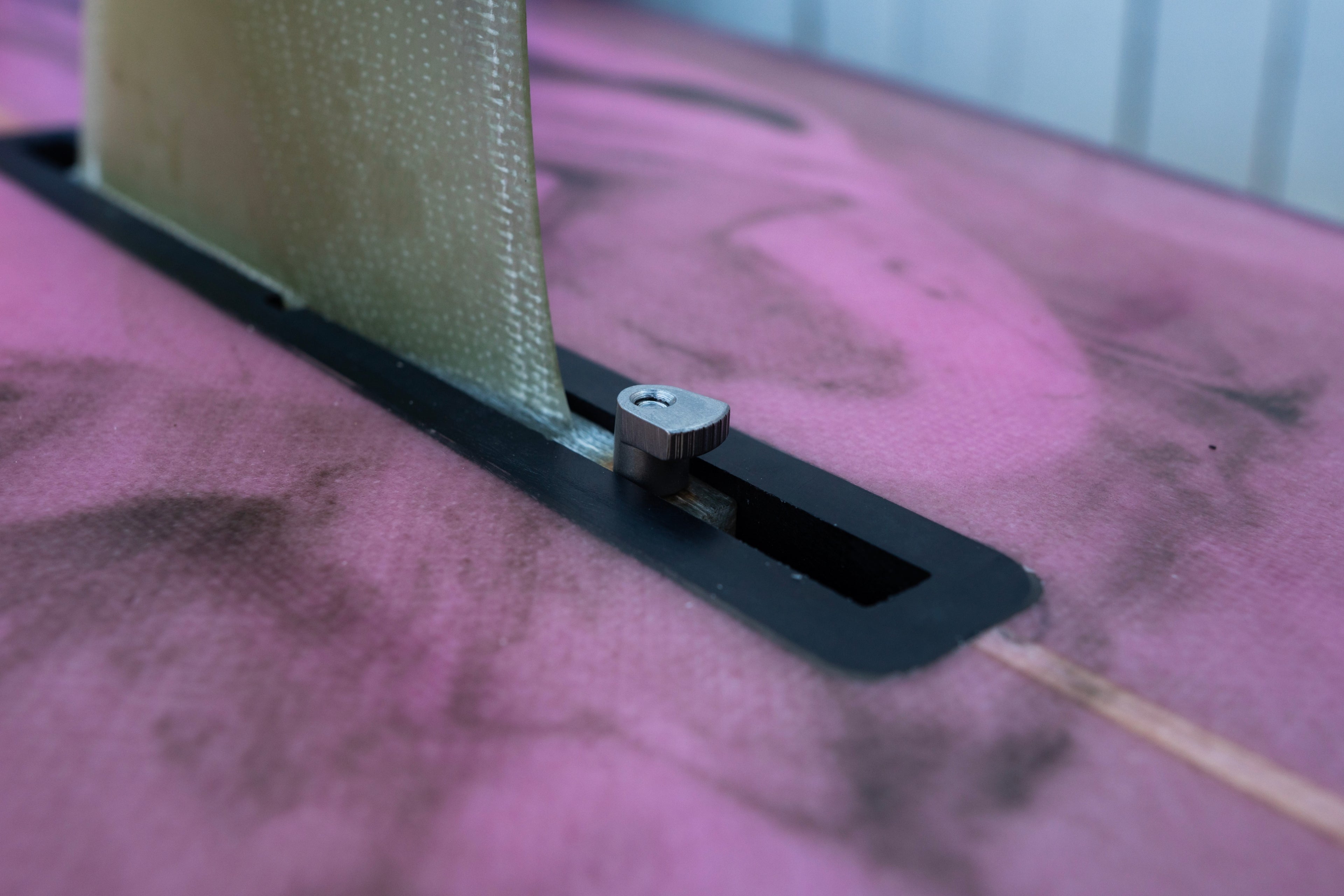Close-up of a metal bracket on a textured pink surface